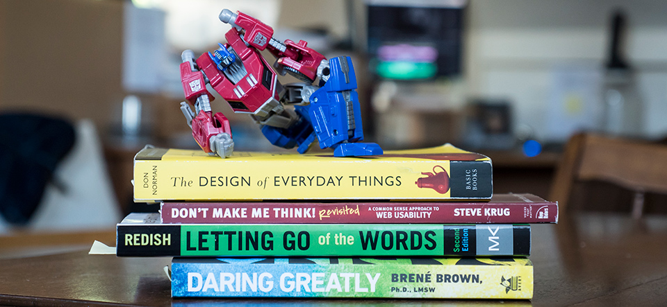 photo of optimus prime toy on top of stack of user experience design books and daring greatly