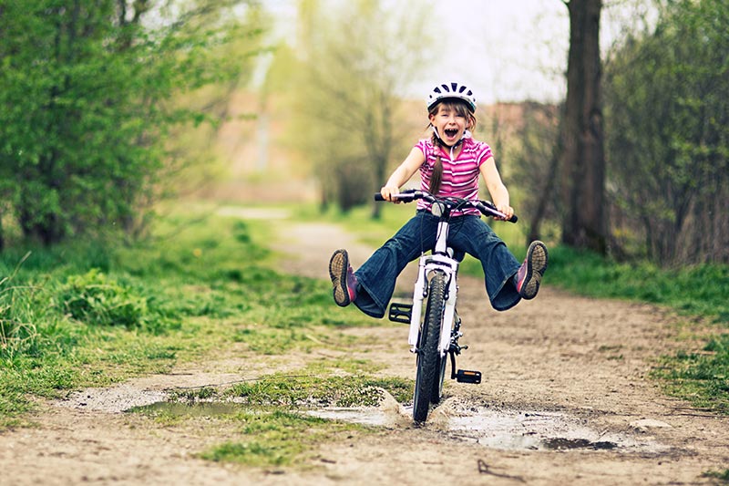 Girl riding her bike through a puddle